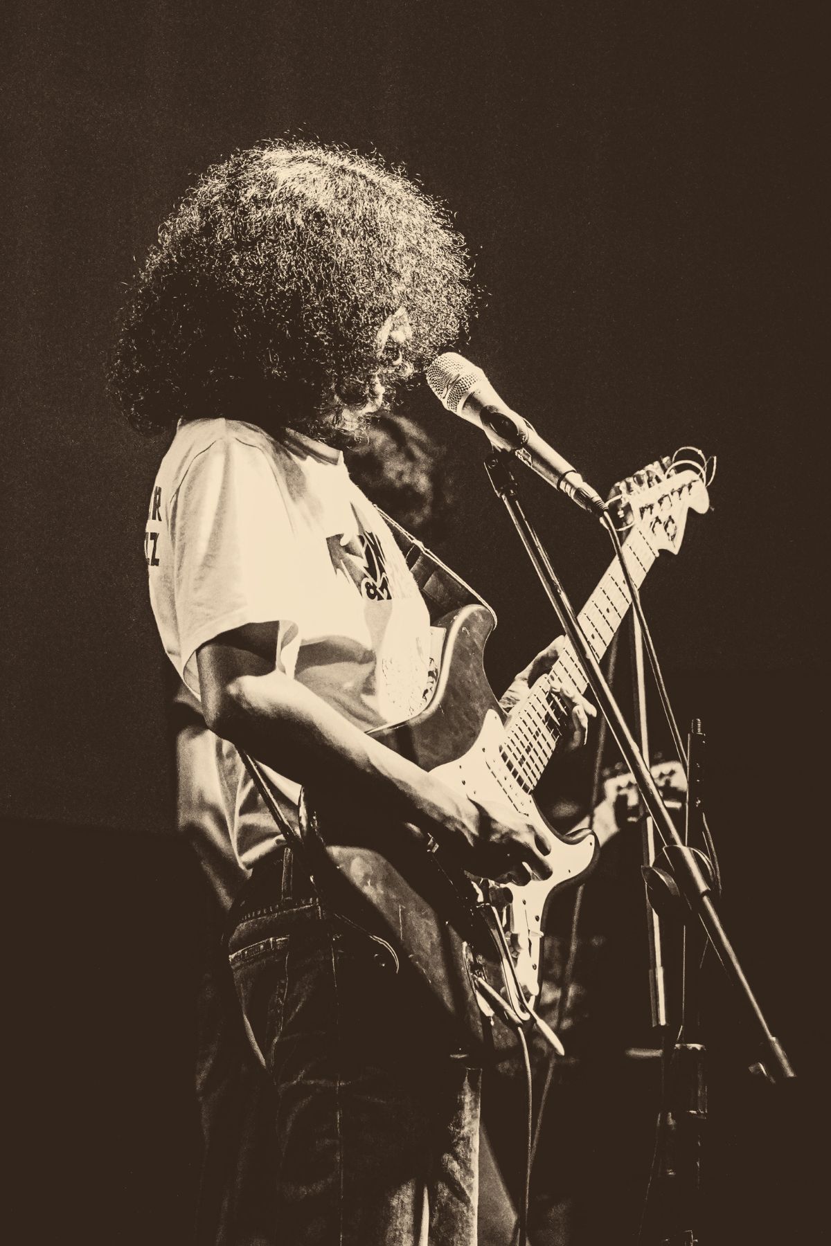A guitarist on stage playing electric guitar, warmly lit